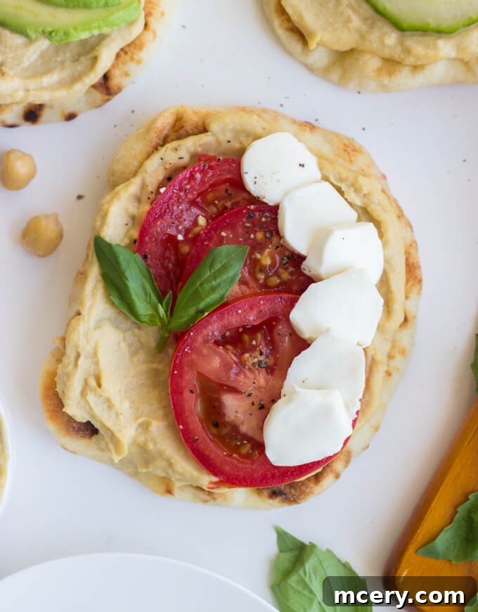 Easy Hummus Naan Toasts: 3 Delicious Variations 7 An appetizing close-up of a mini naan toast with hummus, topped with colorful and fresh ingredients.