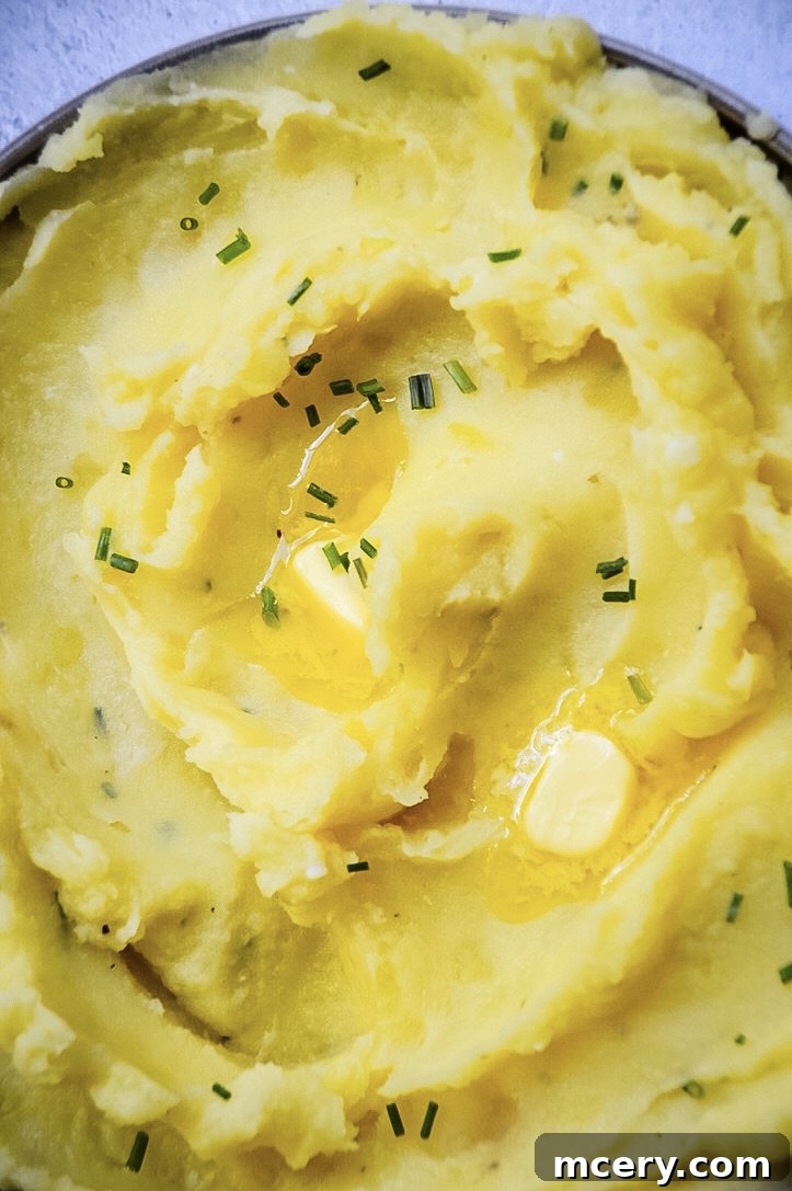 A close-up shot of creamy Instant Pot garlic mashed potatoes, perfectly smooth and fluffy, in a rustic bowl.