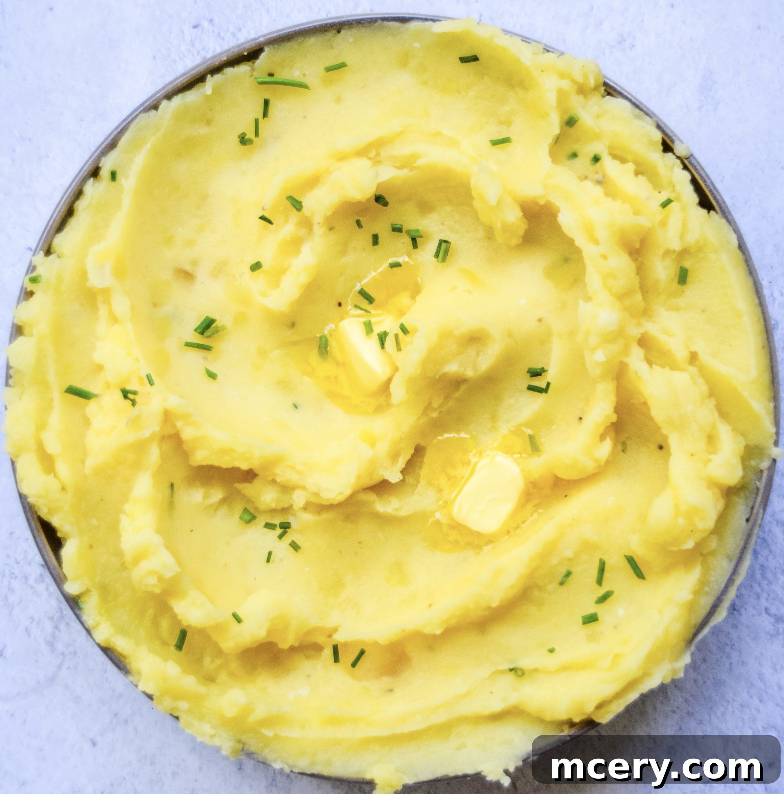 Ingredients for Instant Pot garlic mashed potatoes laid out on a wooden board, including potatoes, garlic, butter, and herbs.