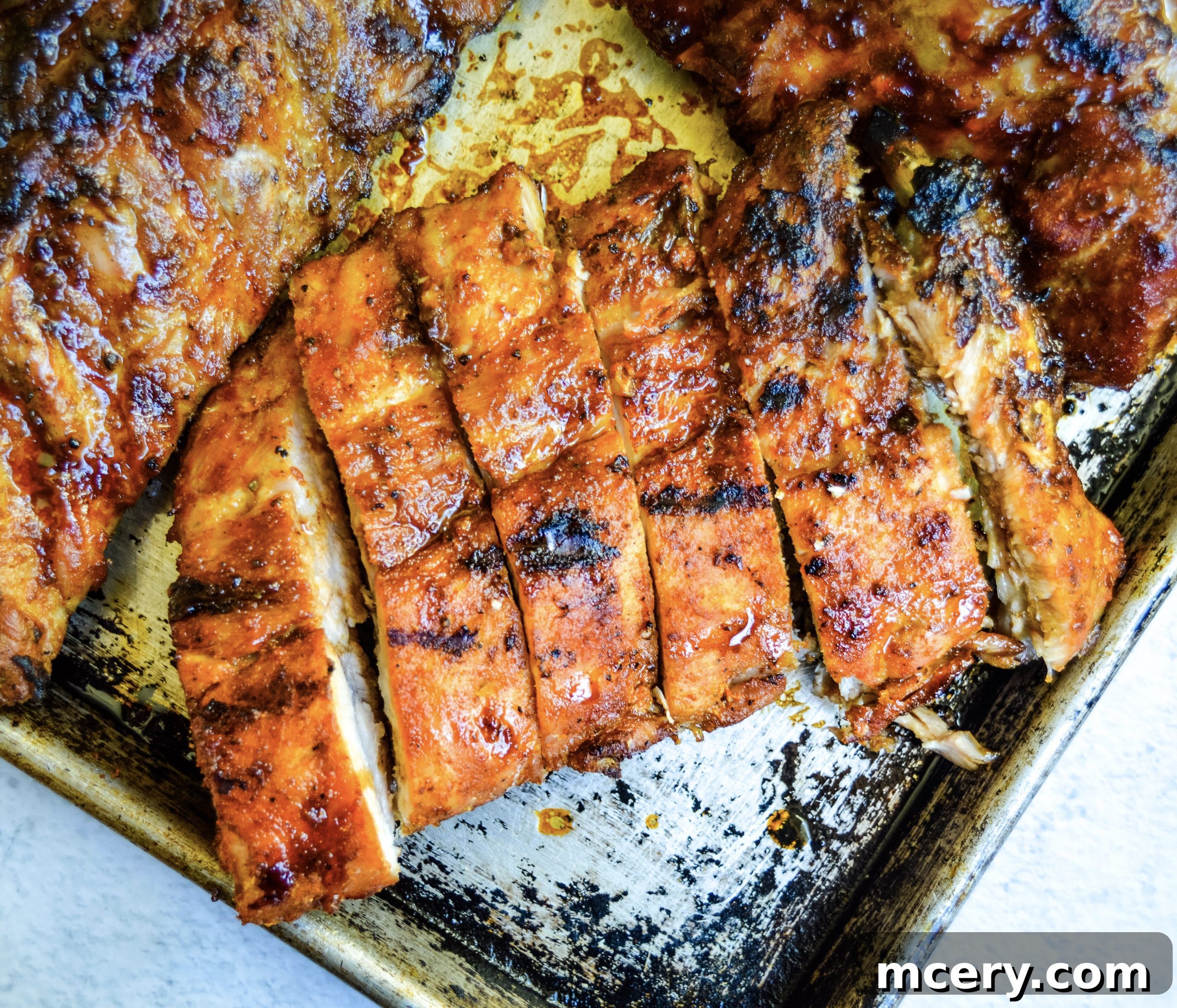 Paleo Rubbed Gas Grilled Pork Ribs 12 A close-up of a hand holding a perfectly grilled and sauced pork rib.