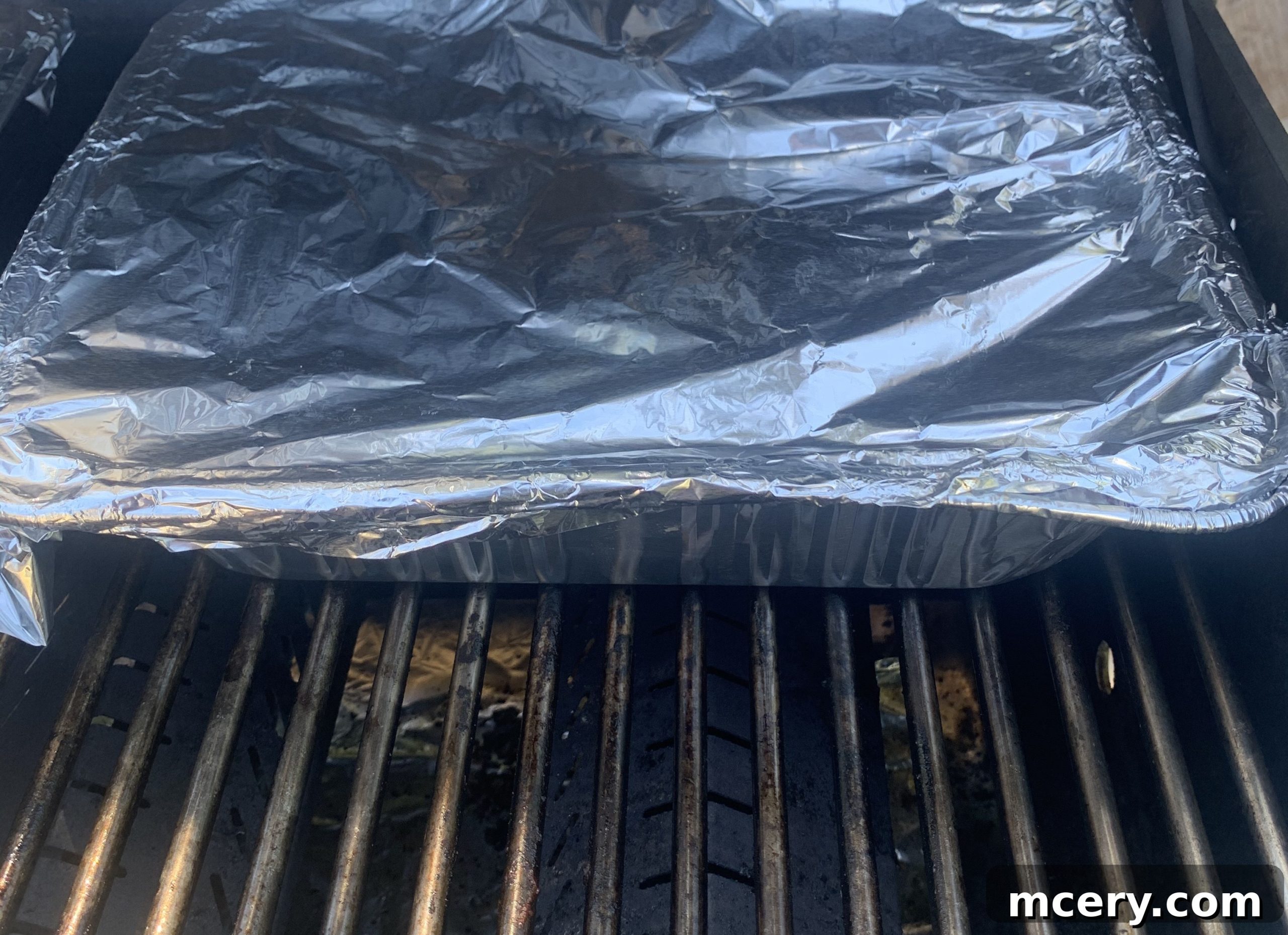 Paleo Rubbed Gas Grilled Pork Ribs 10 Aluminum tray of ribs placed inside a gas grill, cooking over indirect heat.