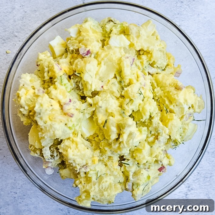 Grandma's Best Potato Salad 3 Close-up view of creamy potato salad, showcasing visible chunks of hard-boiled egg and fresh herbs.
