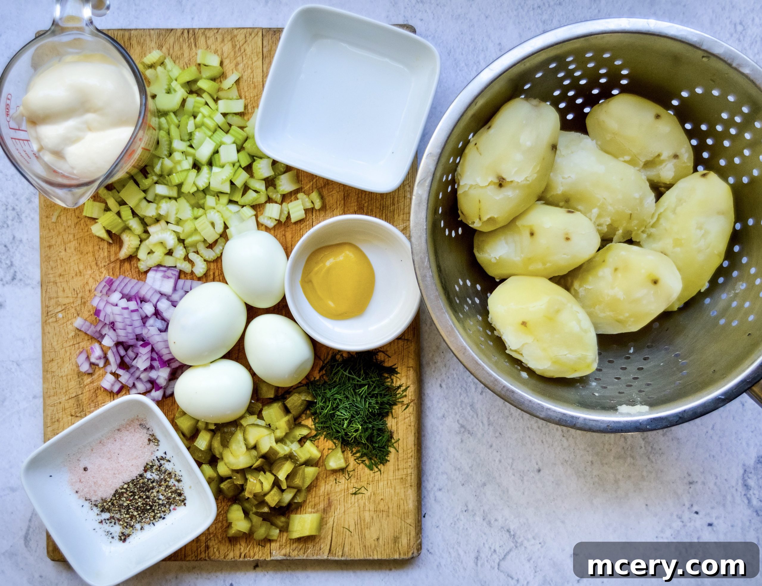 Grandma's Best Potato Salad 5 A flat lay of fresh ingredients including potatoes, eggs, celery, onion, and herbs, prepared for making potato salad.