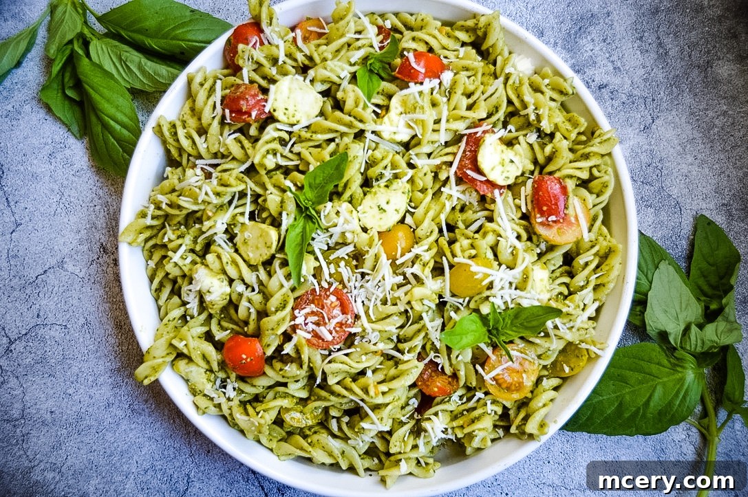 Spinach Pesto Pasta Salad Close Up A close-up shot of the Spinach Pesto Pasta Salad, showing the fusilli pasta coated in green pesto, with fresh mozzarella and cherry tomatoes visible.