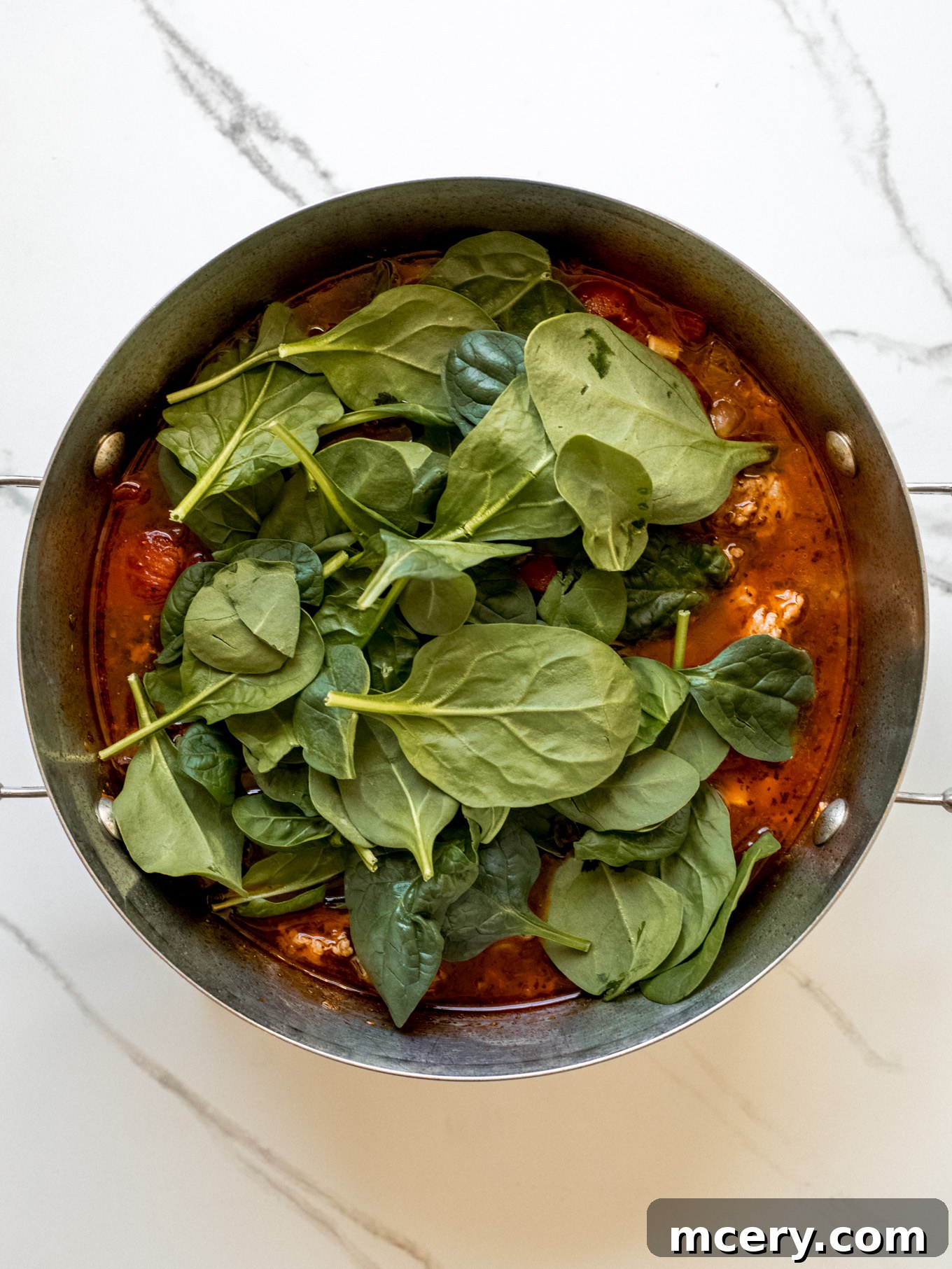 Hearty Italian Sausage Soup 7 Fresh spinach leaves being stirred into a pot of soup.