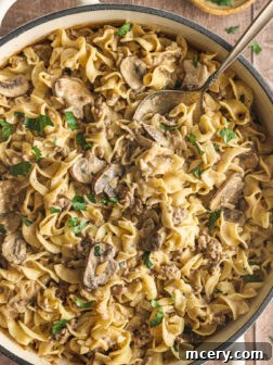 A skillet full of rich, creamy ground beef stroganoff, garnished with fresh parsley.