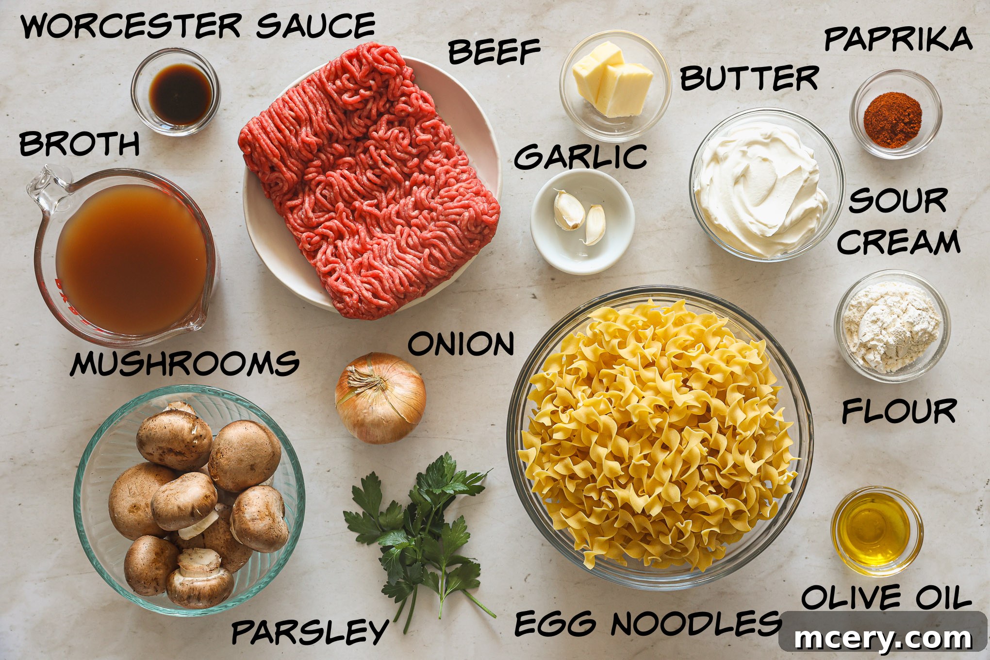 No-Fuss Beef Stroganoff 3 A selection of fresh ingredients including ground beef, mushrooms, onion, garlic, and sour cream laid out for making beef stroganoff.