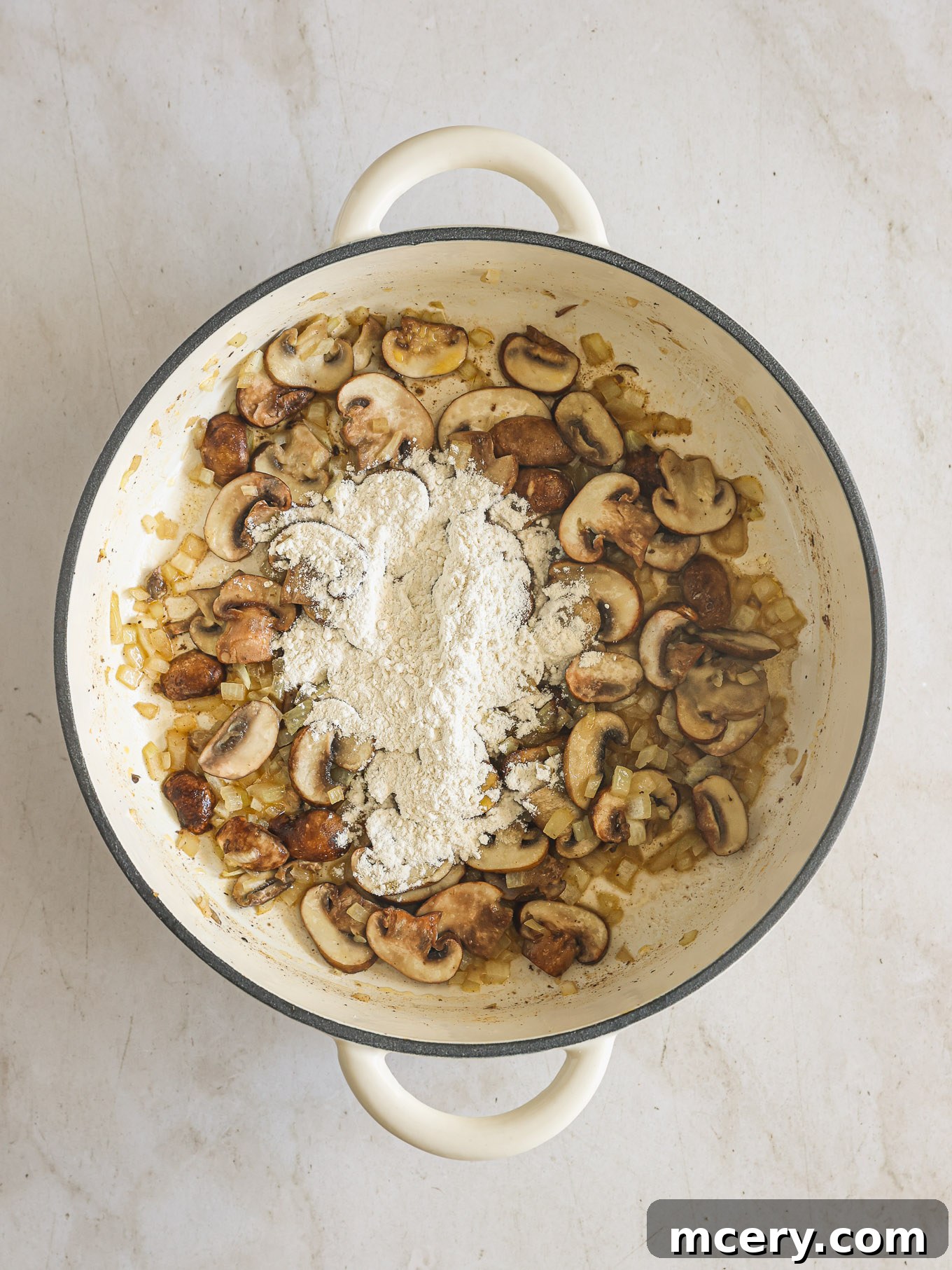No-Fuss Beef Stroganoff 6 Flour being stirred into sautéed mushrooms and onions in a skillet, creating a roux.
