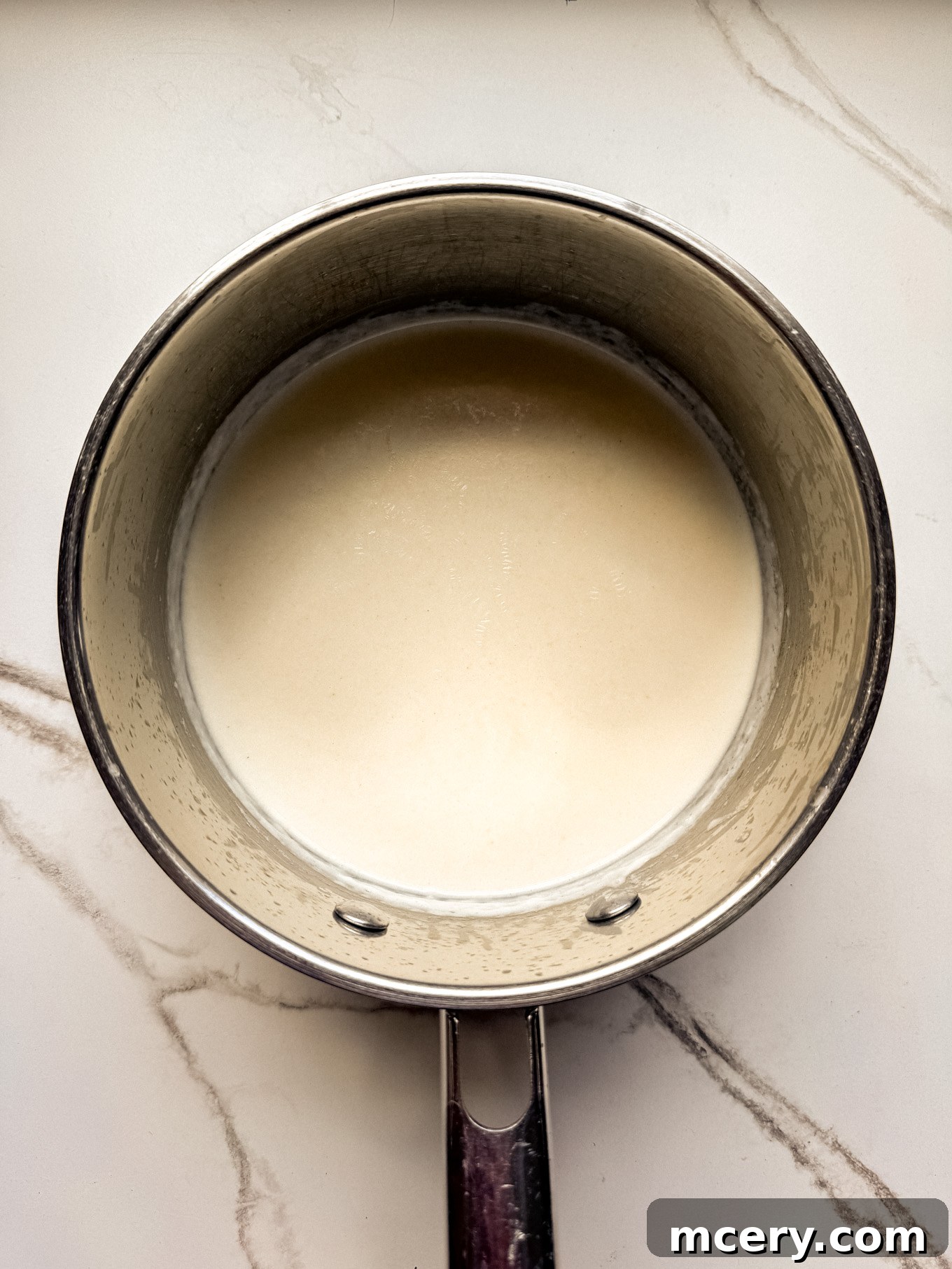 Velvety Smooth Cheese Sauce 5 Half and half being gradually poured into a saucepan with the roux, while being continuously whisked.