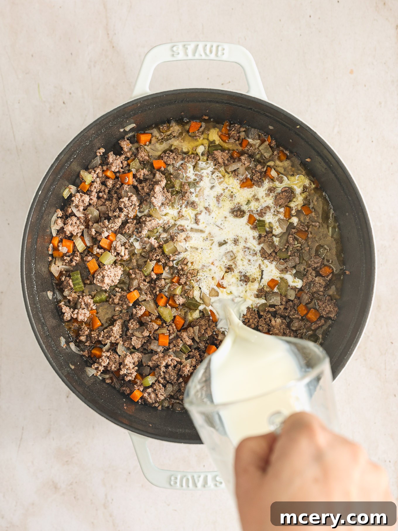 Classic Hearty Bolognese Pasta 7 milk poured into a pot with meat and vegetables.