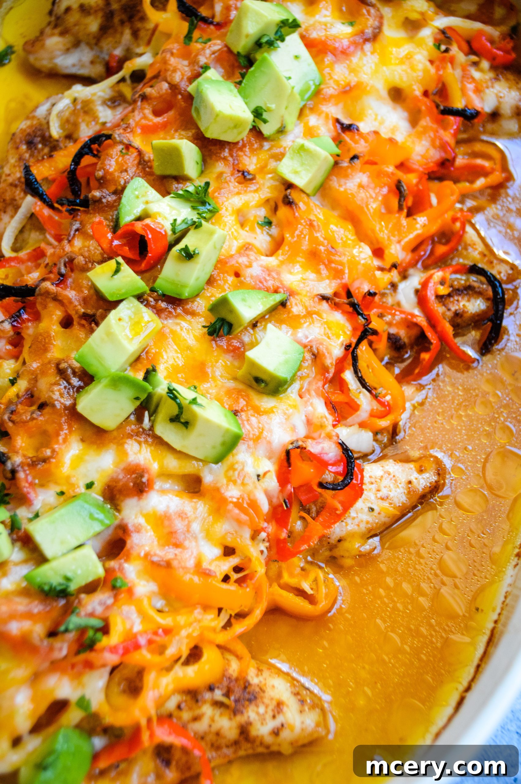 Close-up of baked chicken fajita casserole, showcasing golden-brown melted cheese over chicken and colorful vegetables.