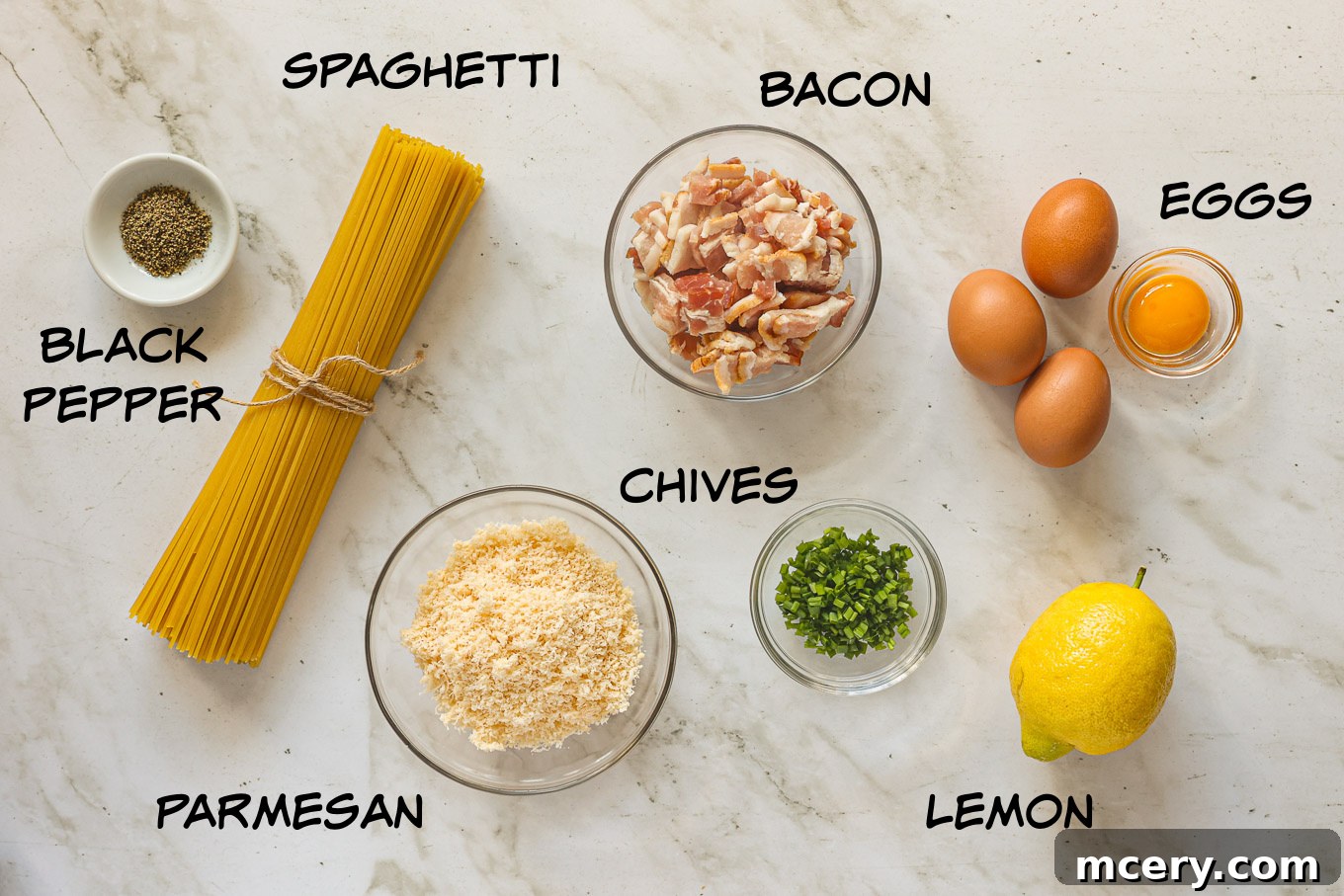 Fresh ingredients laid out for making carbonara pasta, including spaghetti, eggs, cheese, lemon, herbs, and bacon.