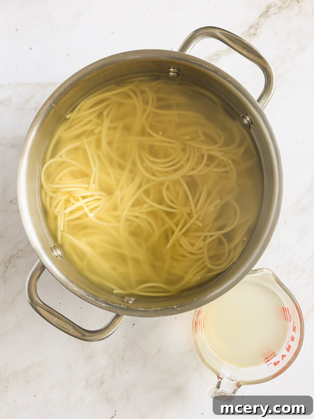Cooked spaghetti draining in a pot of salted water.