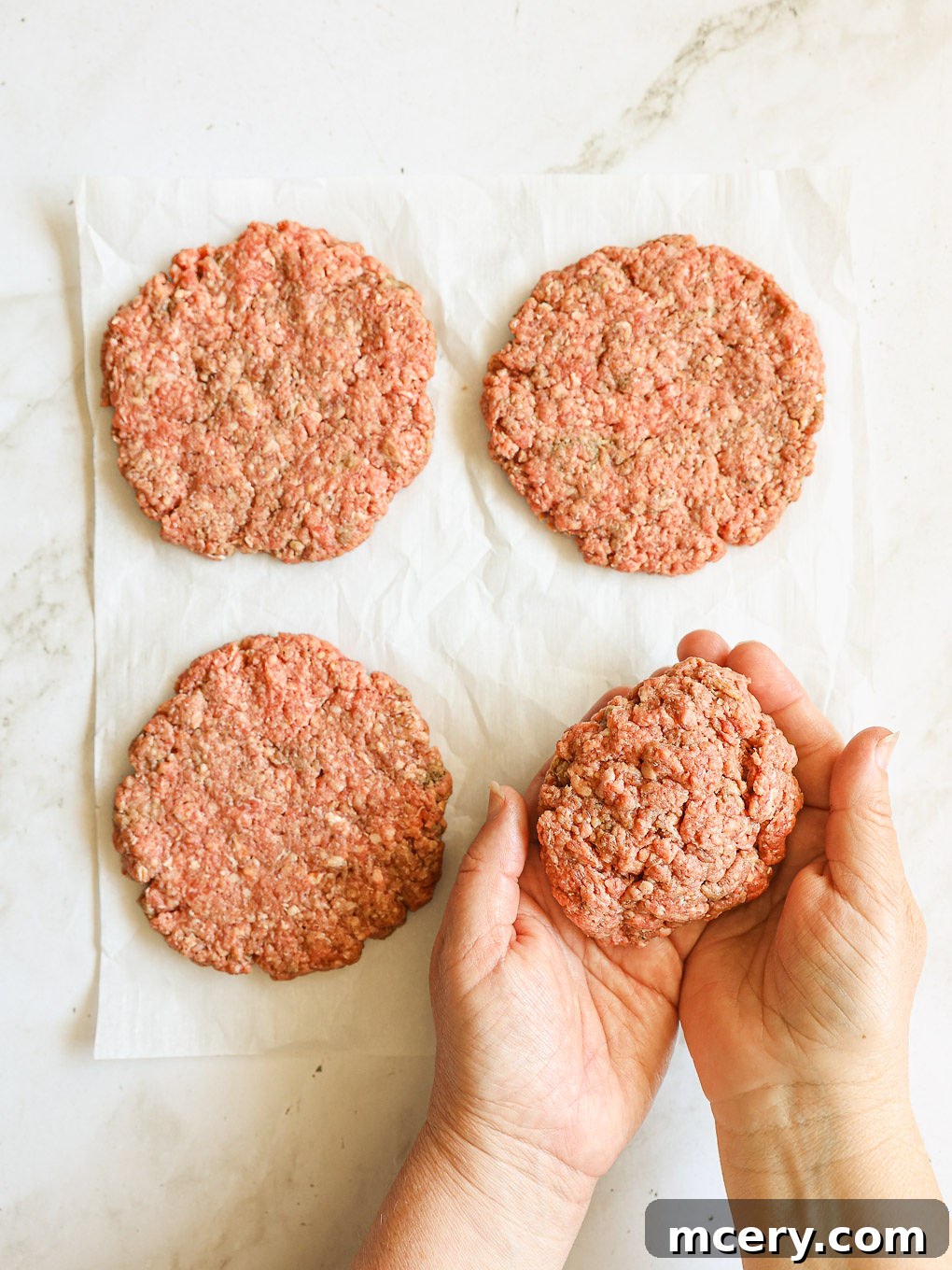 Crafting the Ultimate Homemade Burger 7 Four perfectly shaped beef patties with a slight indent in the center, arranged on parchment paper on a tray, ready for chilling.