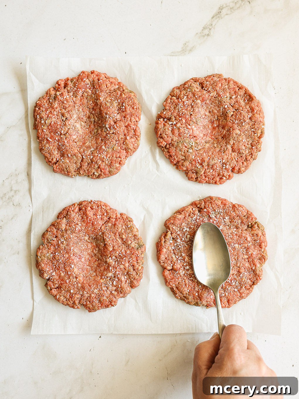 Crafting the Ultimate Homemade Burger 8 A beef patty with a distinct thumbprint indent in its center, demonstrating the technique to prevent puffing.