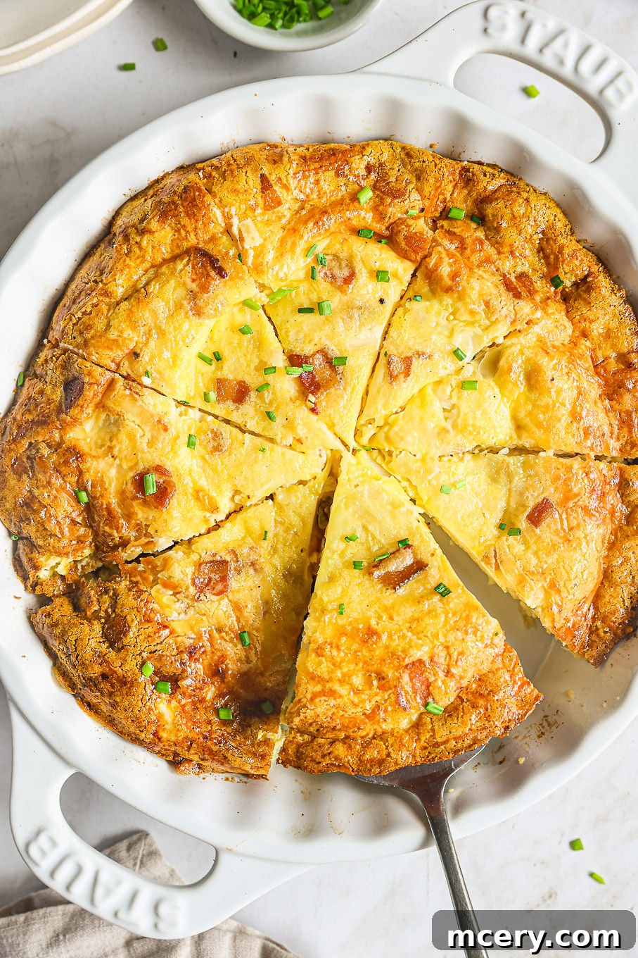 Efsane Hamursuz Kiş Tarifi 2 Sliced crustless quiche in a baking dish, showcasing its golden top and rich, creamy interior filled with bacon and cheese.