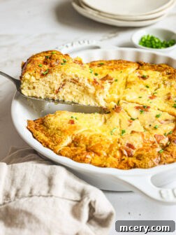 Side view of breakfast quiche in a baking dish, with a slice removed, showing its creamy texture and fillings.