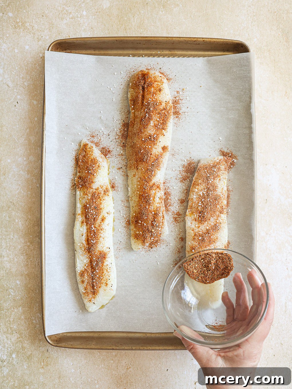 The Ultimate Homemade Fish Tacos 6 Cod fillets on a baking sheet, generously seasoned with the dry spice mixture.