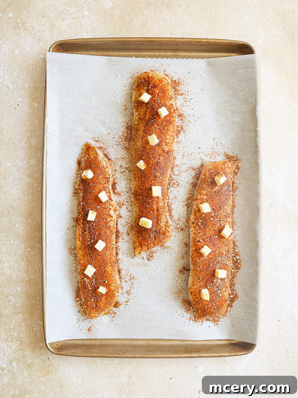 The Ultimate Homemade Fish Tacos 7 Seasoned cod fillets on a baking sheet, topped with small dots of butter.