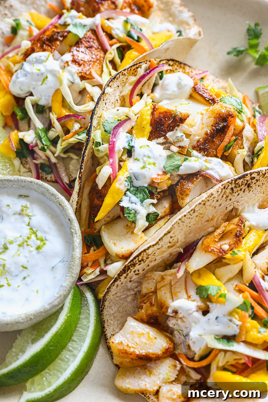 The Ultimate Homemade Fish Tacos 10 Close-up view of two fish tacos with white fish and mango coleslaw, garnished with cilantro.