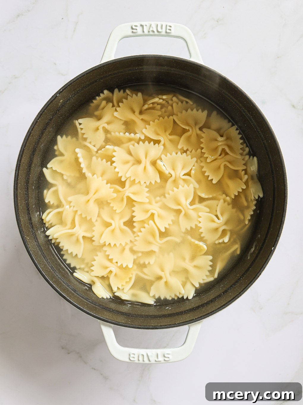 A large pot of perfectly cooked farfalle pasta, drained and ready for the next step of the Cowboy Pasta Salad recipe.