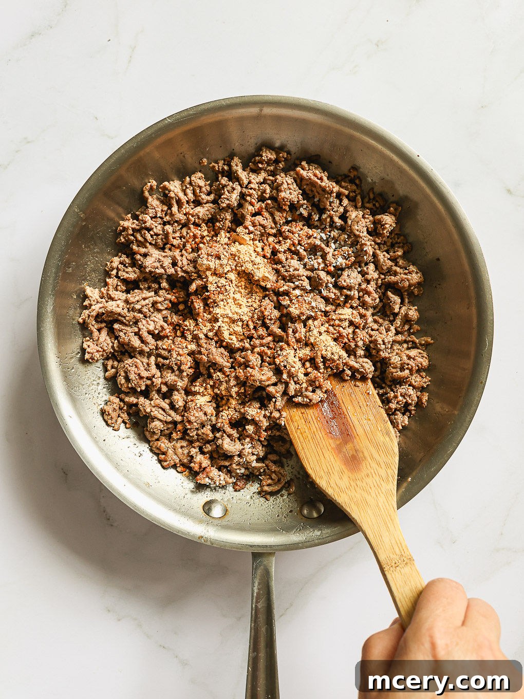 Ground beef browning in a large skillet, broken into small pieces and seasoned with taco seasoning for the Cowboy Pasta Salad.