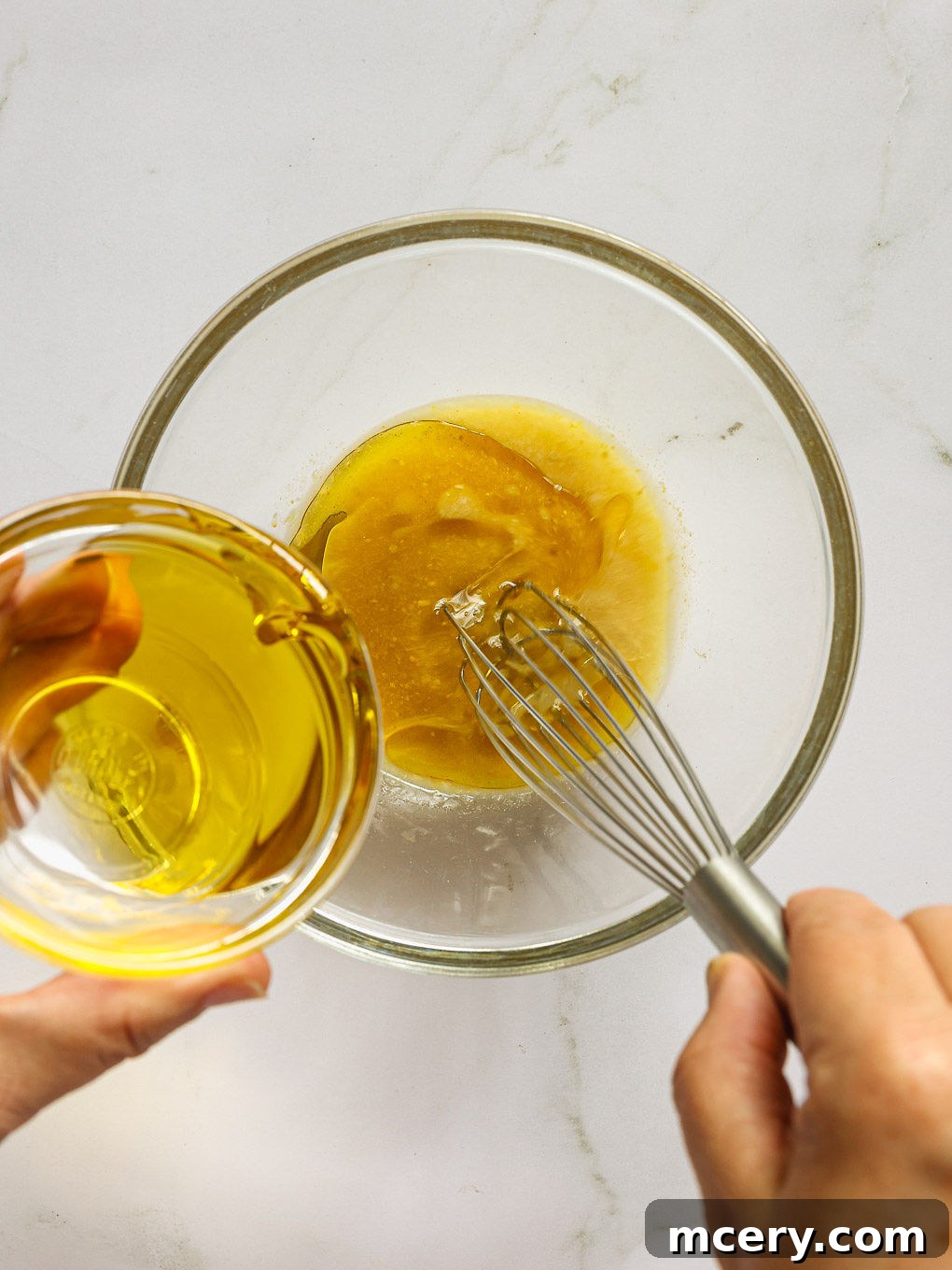 salad vinaigrette in a glass bowl with a whisk.