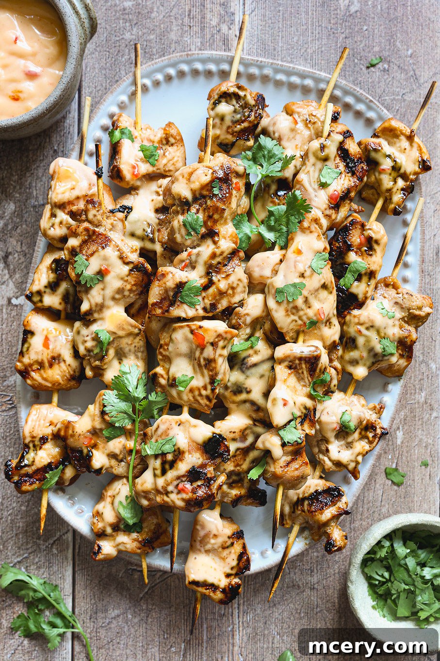 Grilled Bang Bang Chicken Skewers beautifully arranged on a platter, drizzled with creamy, tangy Bang Bang sauce and garnished with fresh cilantro.