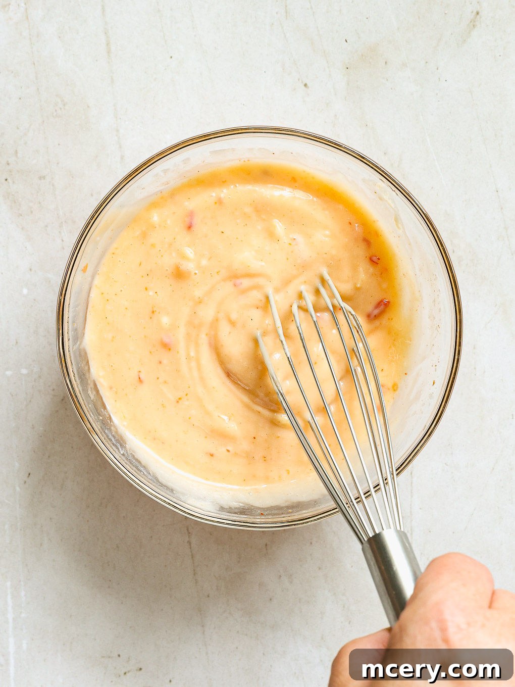 Creamy Bang Bang sauce expertly whisked and ready in a glass bowl, prepared for chilling.