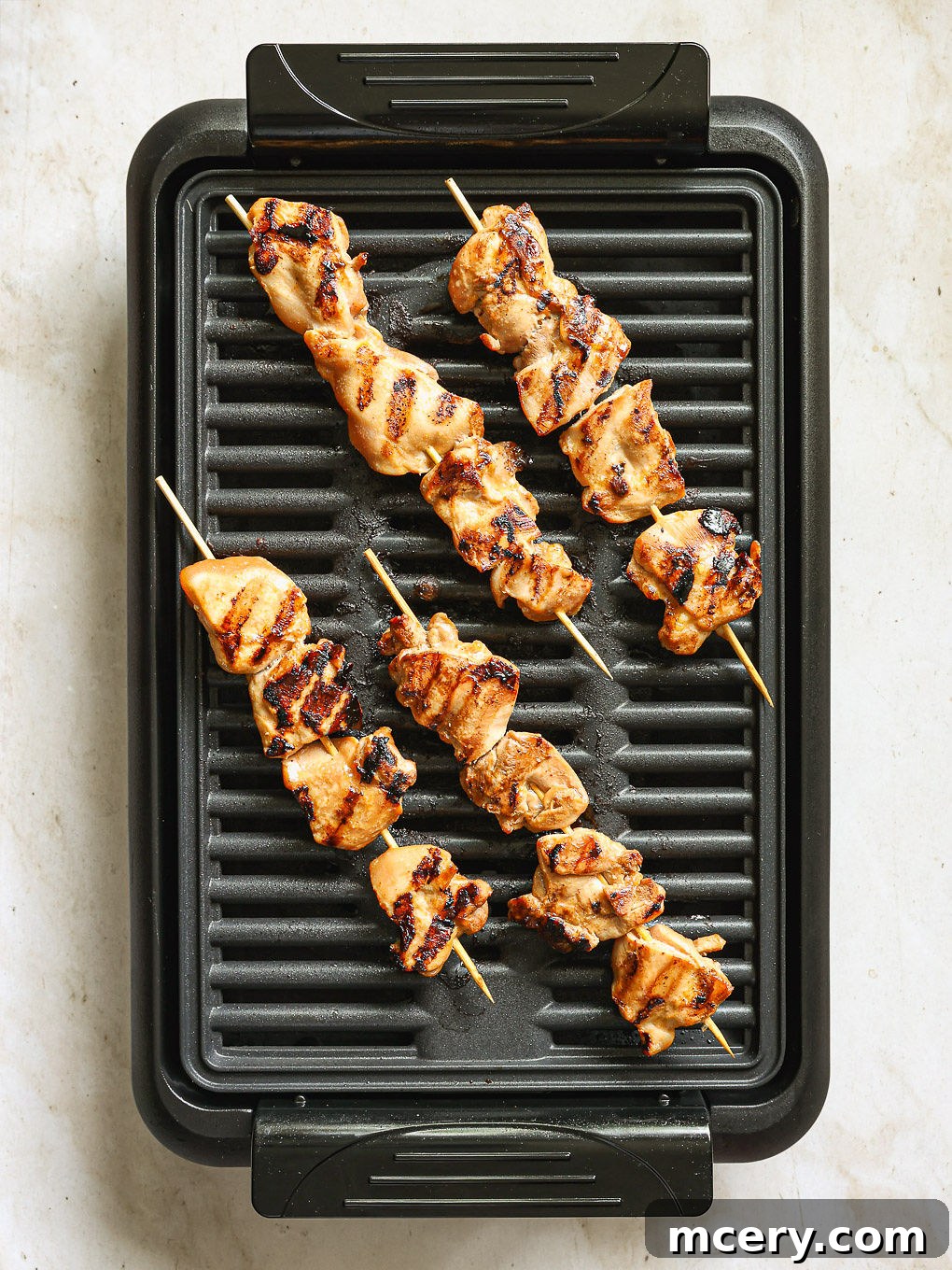 Chicken skewers sizzling on a hot grill pan, developing a beautiful char.