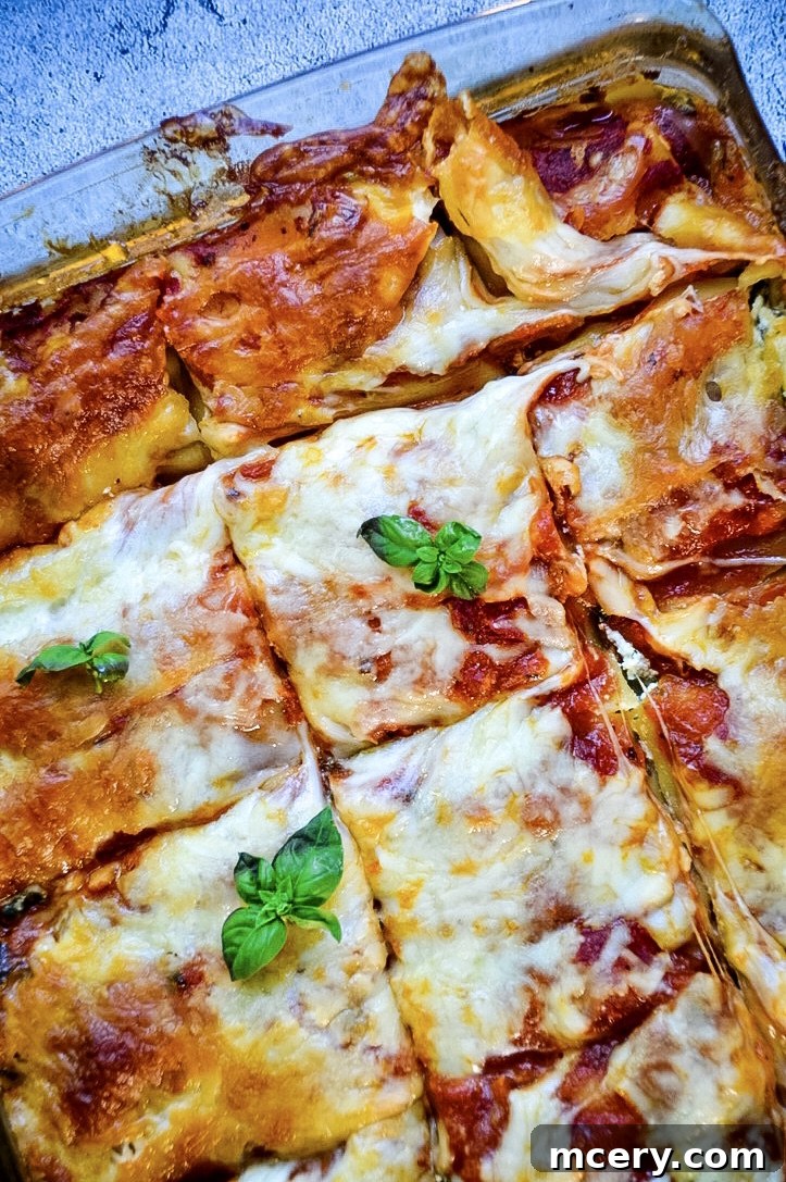 A close-up shot of the carefully assembled spinach lasagna layers before baking, showcasing the neat arrangement of noodles, ricotta, sauce, and cheese.