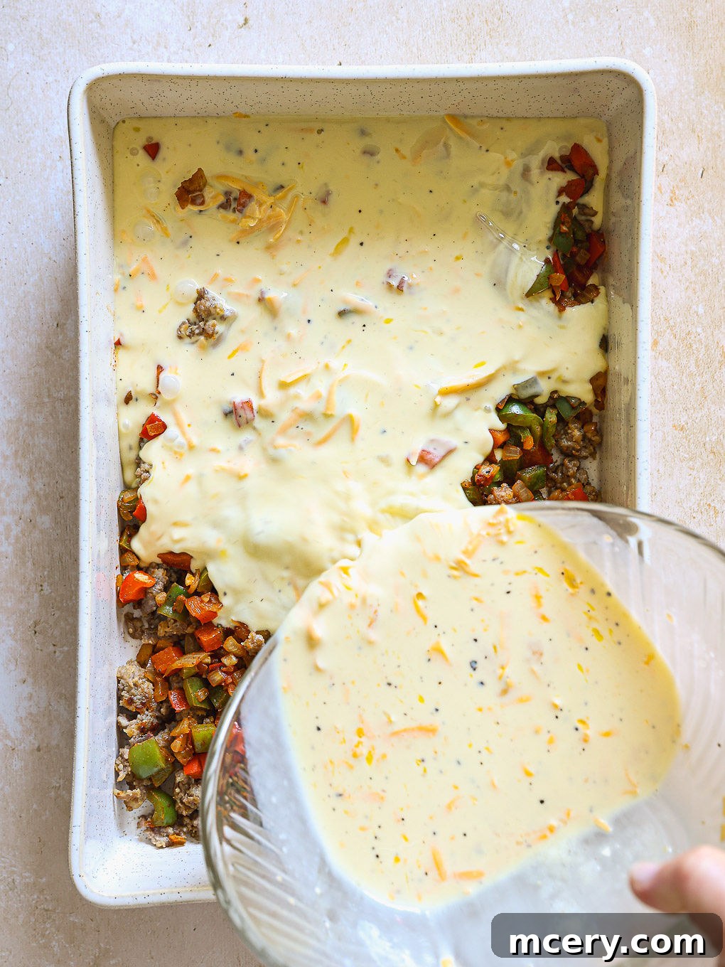 Overnight Southwest Fiesta Bake 8 egg and sausage mixture in a white casserole dish, ready for baking.