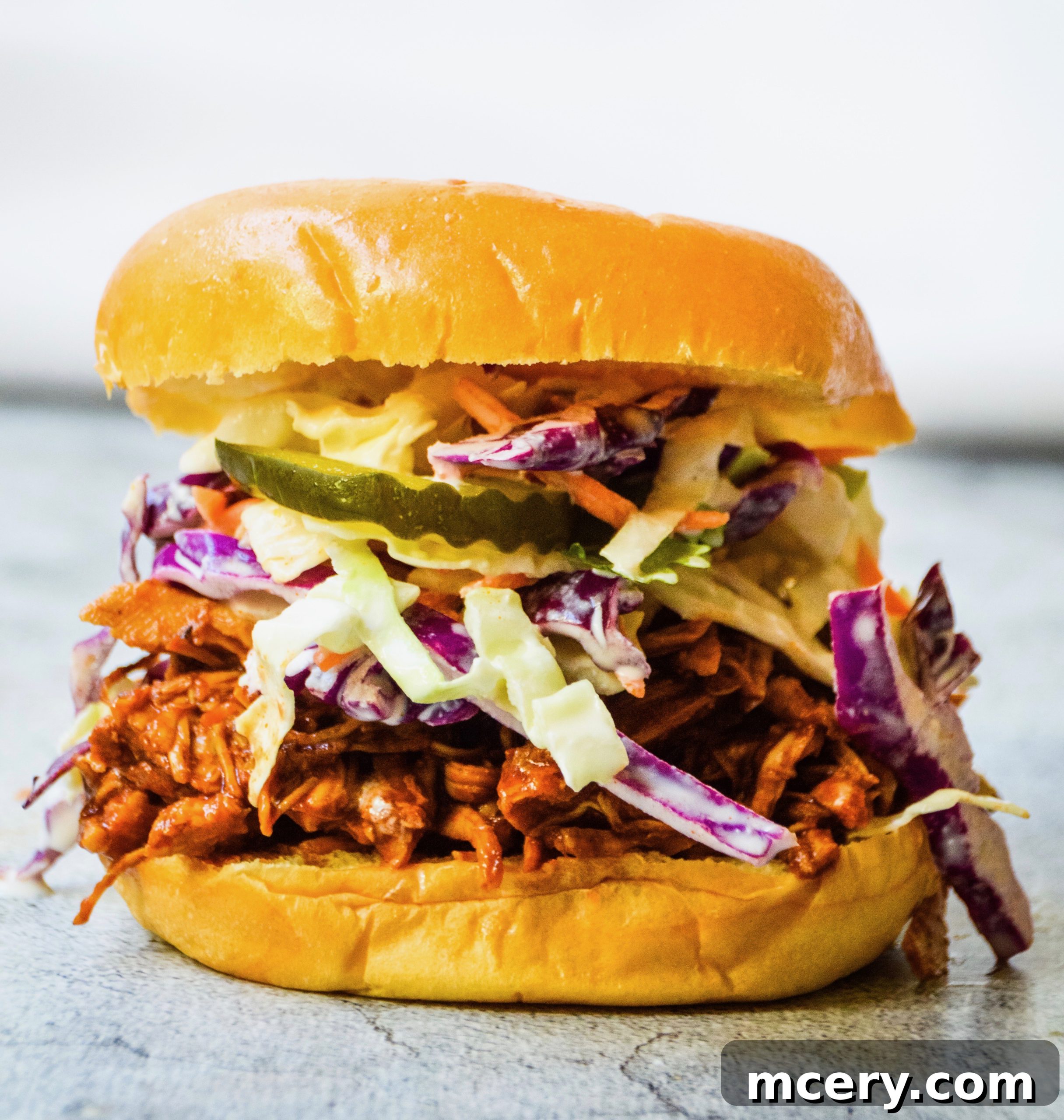 Smoky Pulled Chicken, Crisp Slaw, and Tangy Pickles 3 Close-up of shredded BBQ chicken in a large serving dish, ready to be paired with coleslaw.