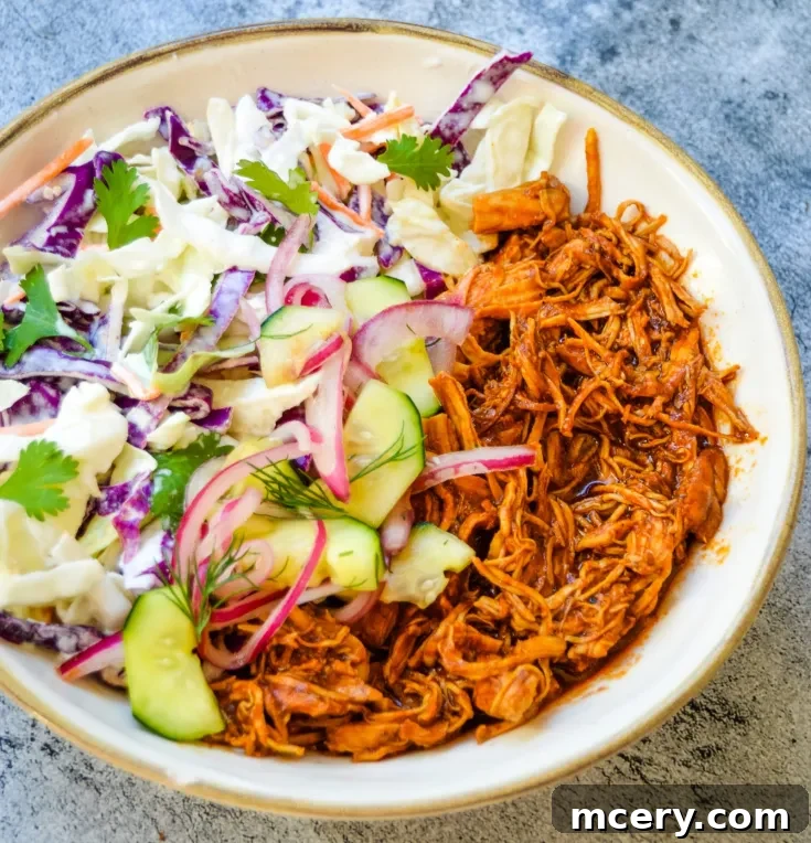 Smoky Pulled Chicken, Crisp Slaw, and Tangy Pickles 8 A vibrant bowl of shredded BBQ chicken and coleslaw, garnished with quick pickled cucumbers, red onions, and fresh herbs, ready to be enjoyed.
