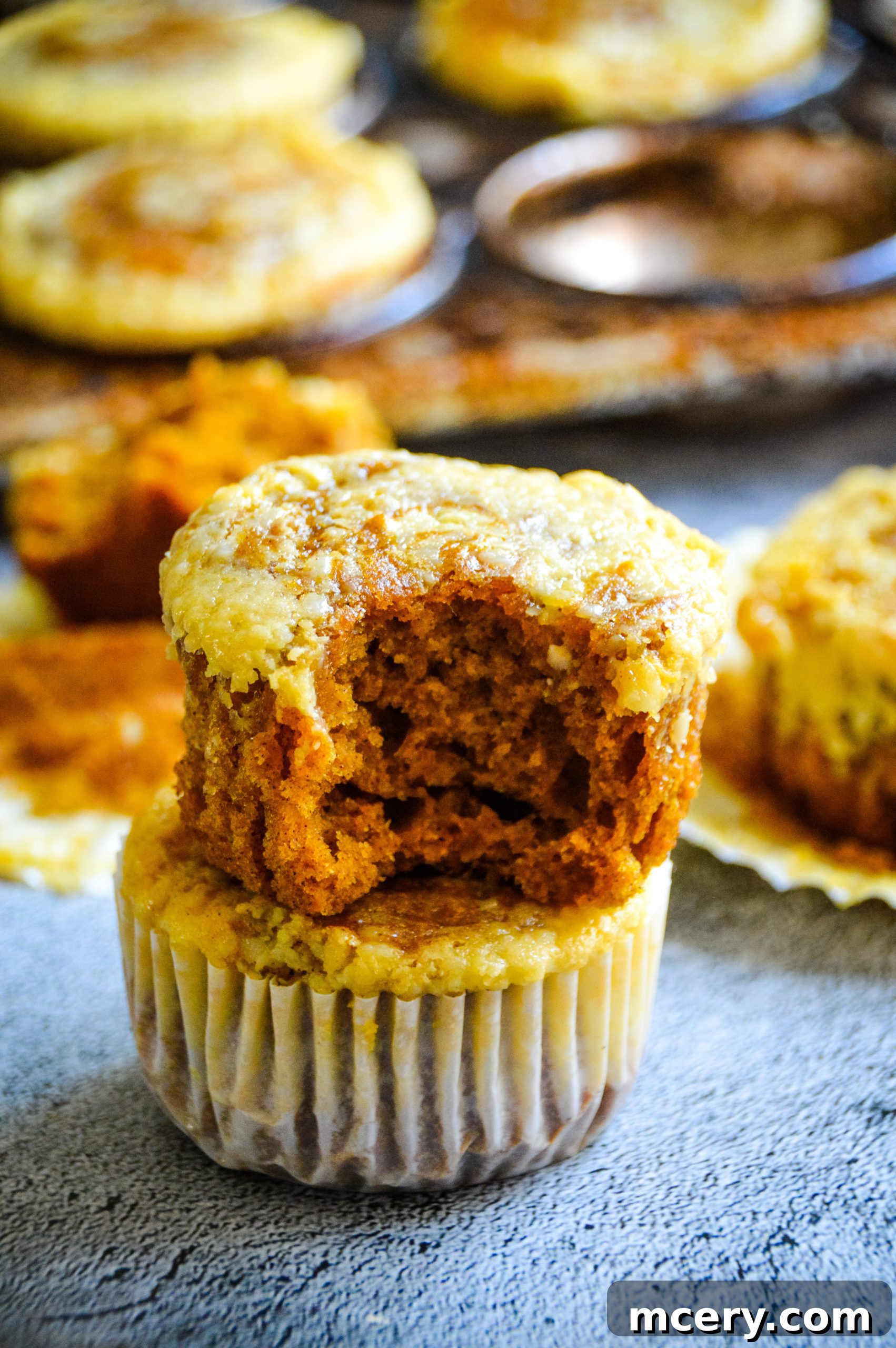 Pumpkin Cheesecake Swirl Muffins 4 A trio of freshly baked pumpkin cream cheese swirl muffins, still warm and inviting, arranged beautifully to highlight their golden tops and creamy centers.