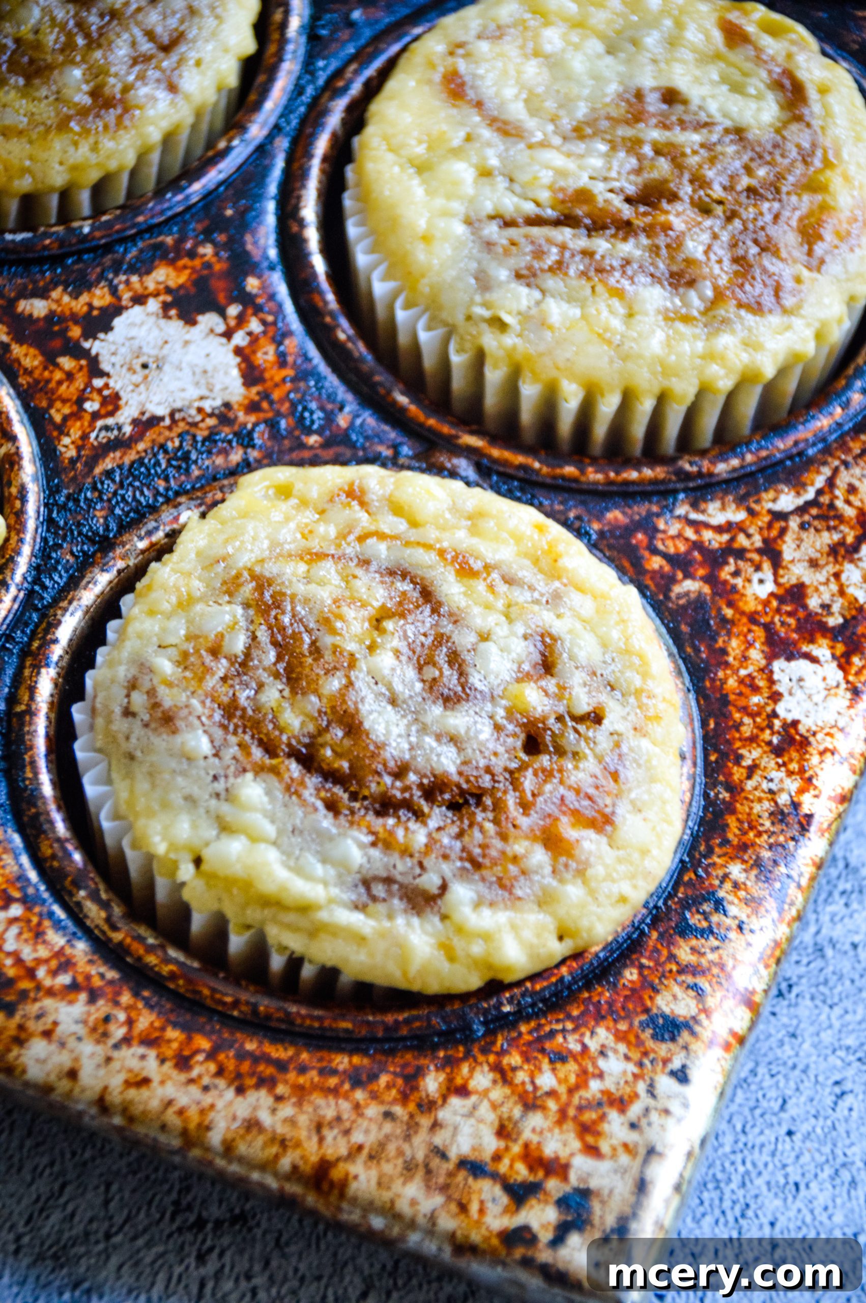 Pumpkin Cheesecake Swirl Muffins 5 An overhead shot of several baked pumpkin cream cheese swirl muffins, some on a cooling rack and others ready to be served, emphasizing the inviting texture and swirl.