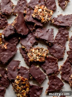A large piece of homemade dark chocolate almond bark, showing the layered texture with nuts and seeds.