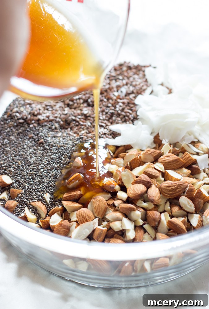 Midnight Almond Bark 4 Raw almonds, chia seeds, flax seeds, and coconut flakes mixed with honey and coconut oil in a bowl.