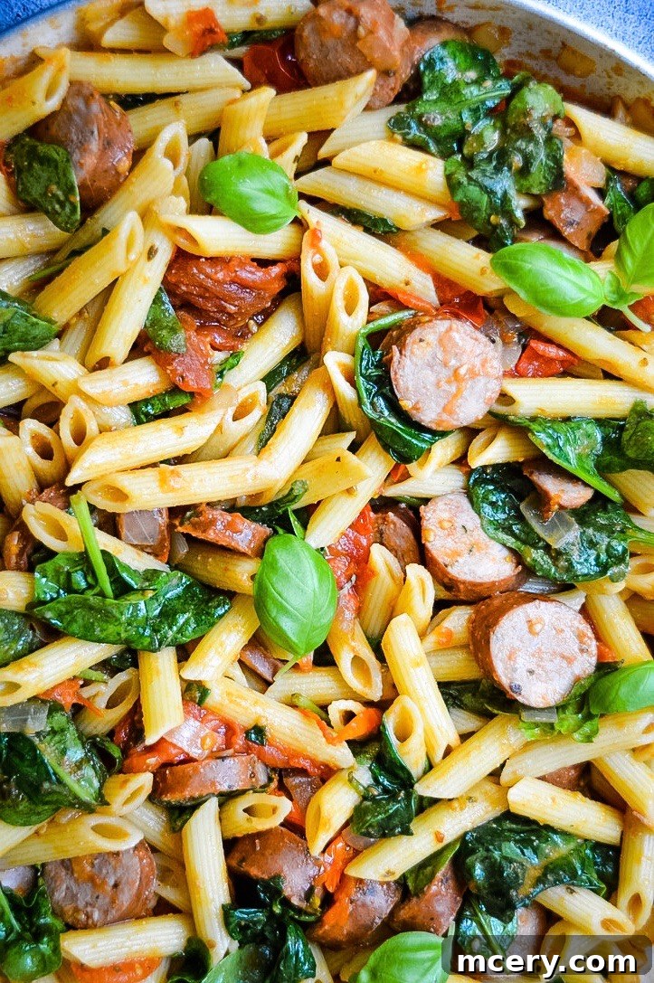 Hearty Tomato Spinach and Sausage Pasta 4 An appetizing close-up of the Easy Tomato Spinach and Sausage Pasta in a pan, showing the rich sauce and perfectly cooked ingredients.