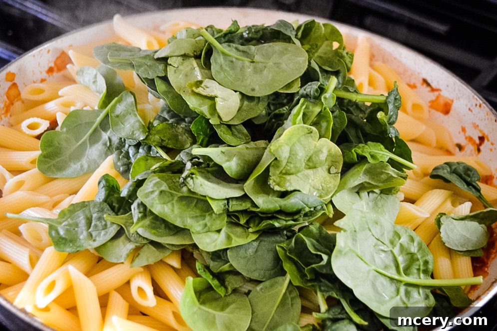 Hearty Tomato Spinach and Sausage Pasta 8 A large serving bowl filled with Tomato Spinach and Sausage Pasta, perfect for a family dinner.