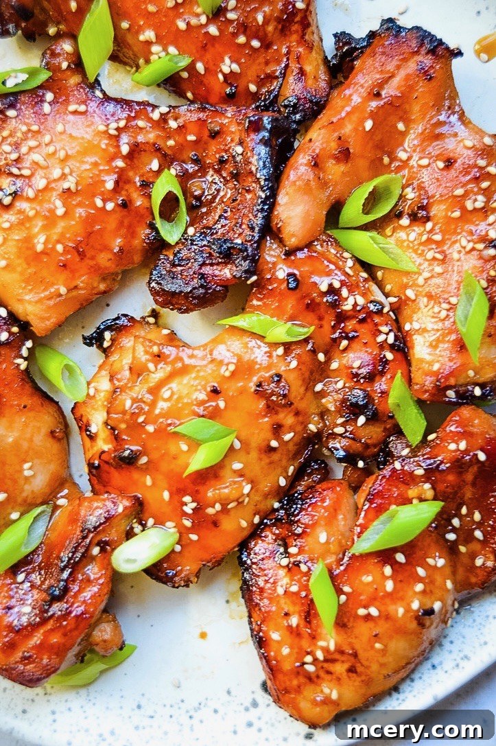 Sticky Soy Chicken Thighs 2 Perfectly golden brown Asian Glazed Chicken Thighs served on a platter, garnished with fresh green onions and sesame seeds.
