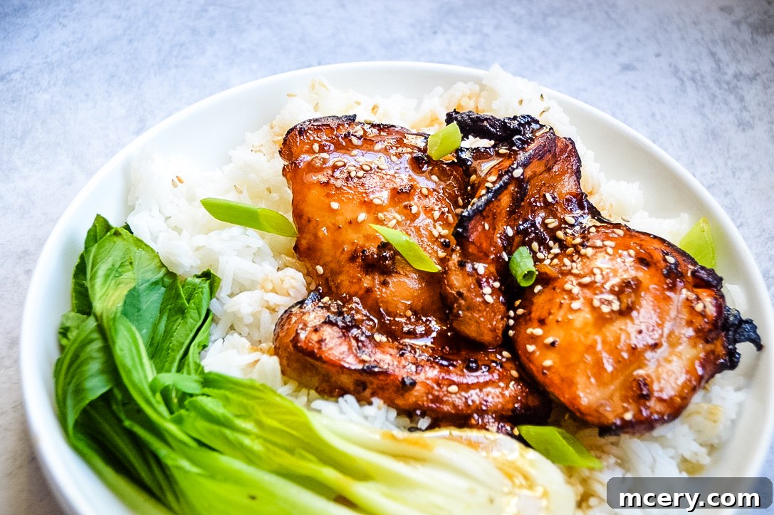Sticky Soy Chicken Thighs 4 A vibrant close-up of Asian Glazed Chicken Thighs being served, showing the glistening sauce and fresh green onion garnish, with steam rising.