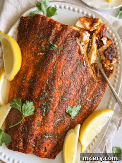 Oven-baked blackened salmon fillets served with lemon wedges.