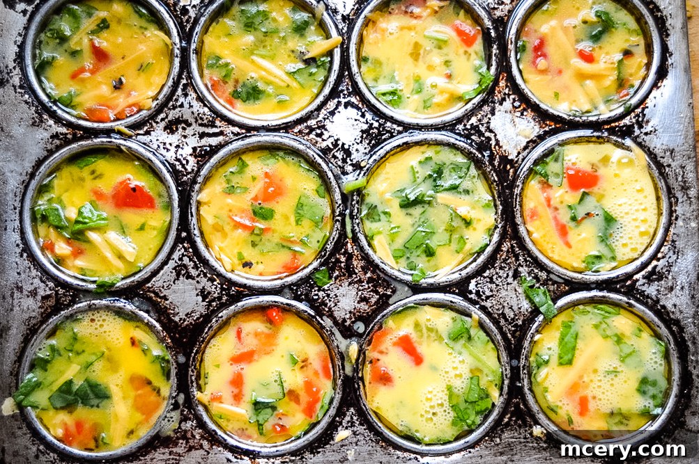 Savory Spinach and Roasted Red Pepper Egg Bites 4 Several appetizing roasted red pepper and spinach egg cups artfully arranged on a clean white surface, showcasing their delicious and wholesome appeal.