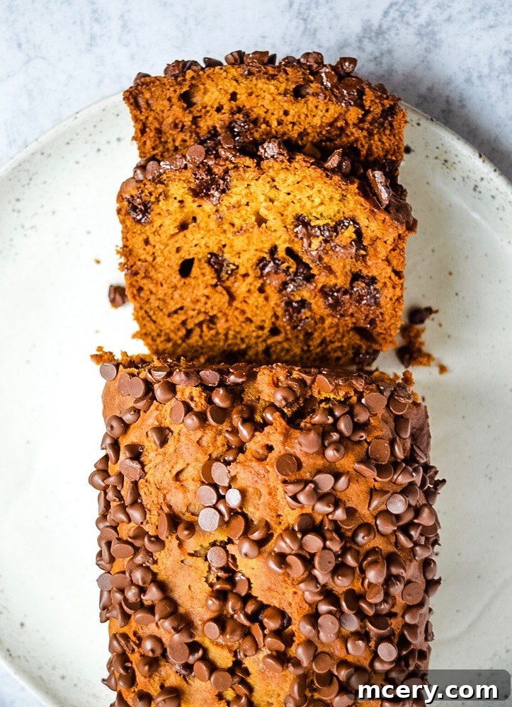 A single slice of moist Pumpkin Chocolate Chip Bread on a white plate with a fork, ready to be enjoyed as a comforting fall snack or dessert.