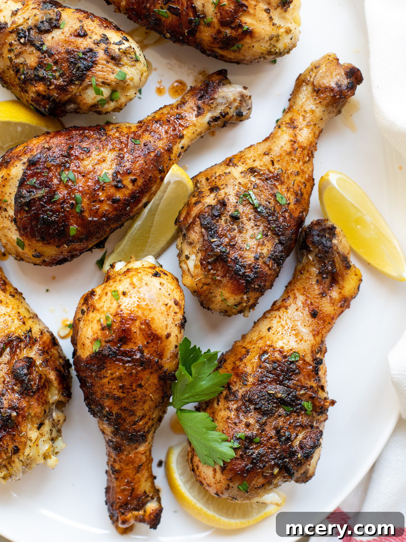 Smoky Grilled Chicken Drumsticks 7 A close-up shot of perfectly grilled chicken legs, golden brown and garnished with fresh herbs, presented on a white serving platter.