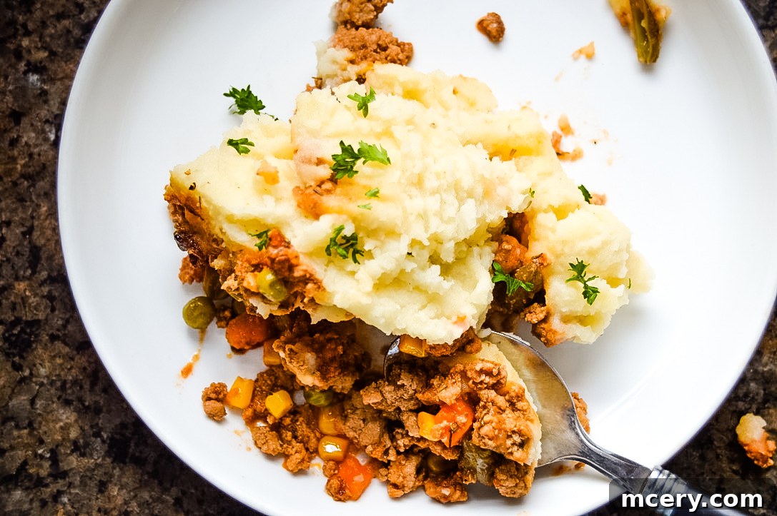 Hearty Slow Cooker Shepherds Pie 3 A close-up shot of a slow cooker filled with a rich, savory meat and vegetable mixture, topped with a thick layer of creamy mashed potatoes.