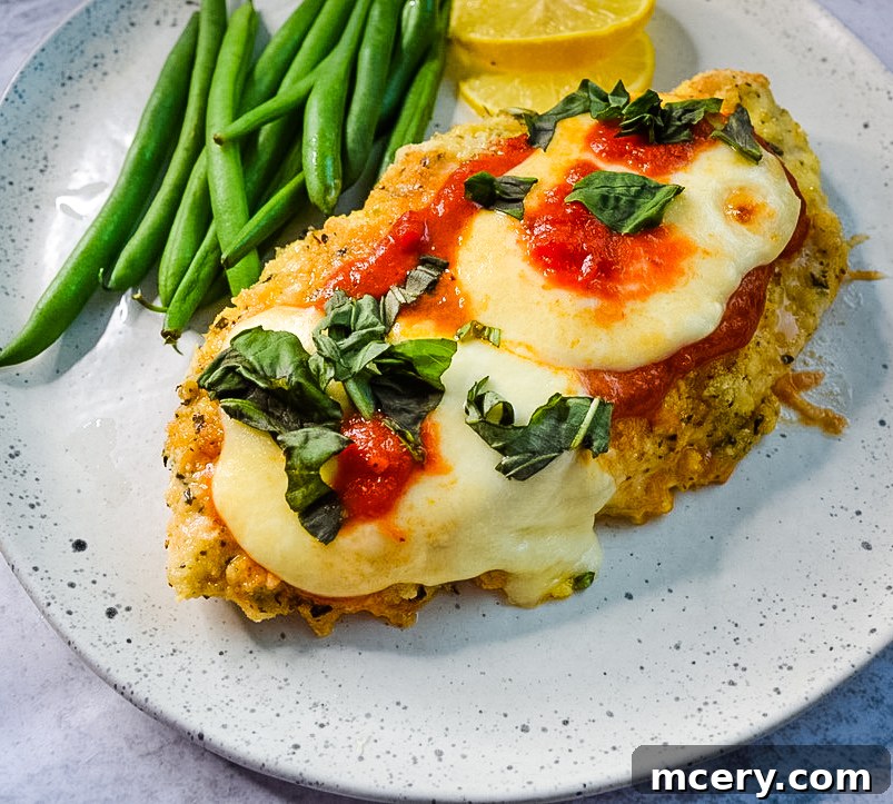 Crispy Keto Chicken Parmesan Bake 3 Two pieces of uncooked, breaded chicken cutlets ready for baking on a parchment-lined sheet.