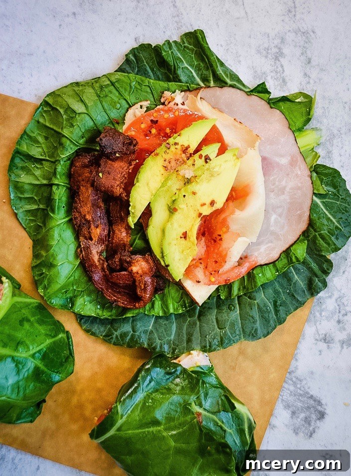 Golden State Collard Sandwich 3 A close-up of a partially eaten California Collard Sub, revealing layers of sliced deli meat, avocado, and tomato wrapped snugly in a collard green leaf.