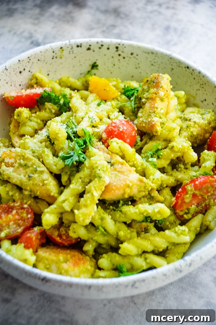 Emerald Pesto Chicken Pasta 5 A beautifully plated bowl of Chicken Pesto Pasta garnished with fresh basil leaves and parmesan cheese.